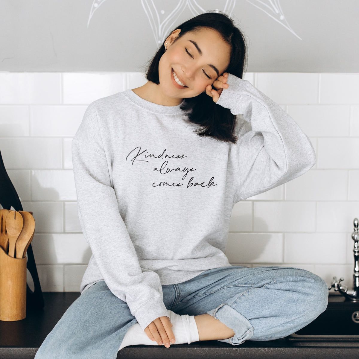 Frau in hellem Sweatshirt mit dem Schriftzug Kindness always comes back